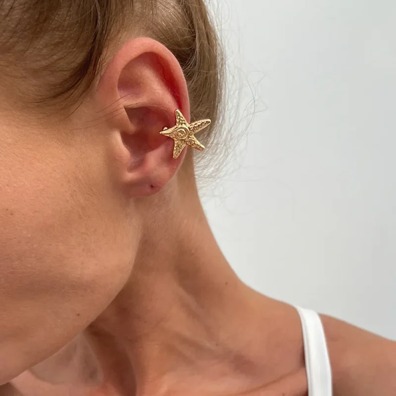 Mini étoile de mer dorée en clip portée sur le haut de l'oreille