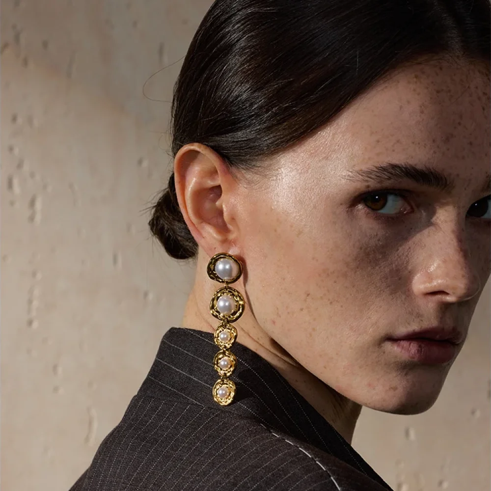 Longue boucle d'oreille dorée à perles baroques portée