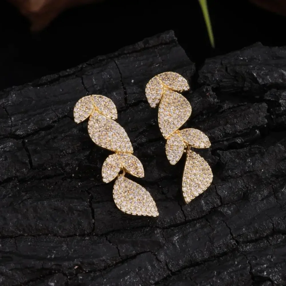 Boucles d'oreilles feuilles dorées scintillantes sur bois sombre