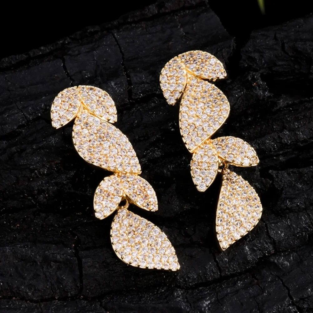 Boucles d'oreilles feuilles pavées dorées sur fond noir
