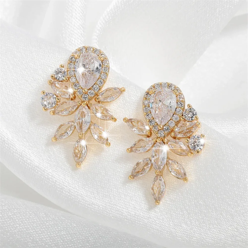 Boucles d'oreilles goutte marquise dorées sur tissu blanc