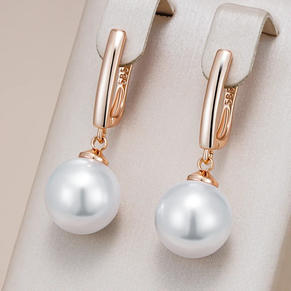 Boucles d'oreilles perle or rose suspendues à un présentoir