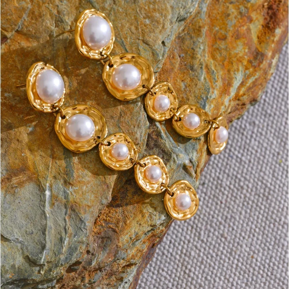 Boucles d'oreilles perles baroques dorées posées sur une pierre