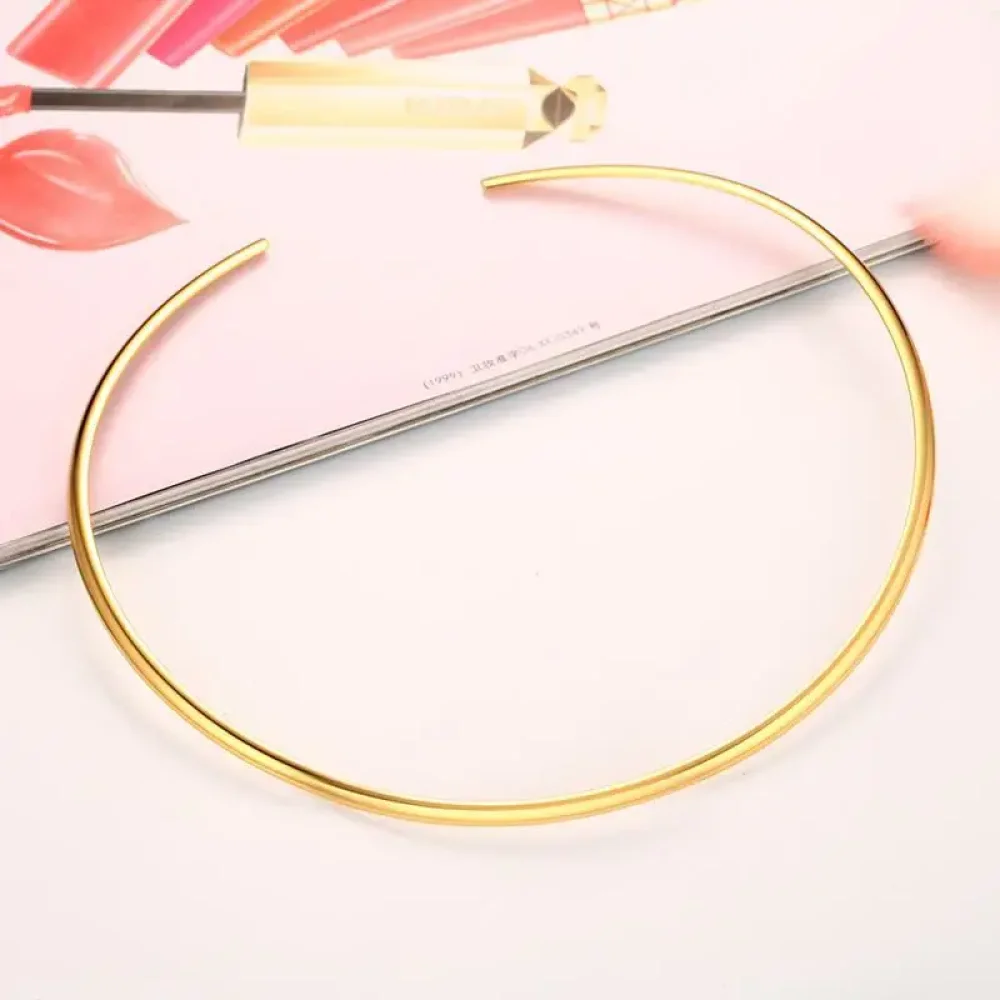 Collier torque doré rigide ouvert posé à plat