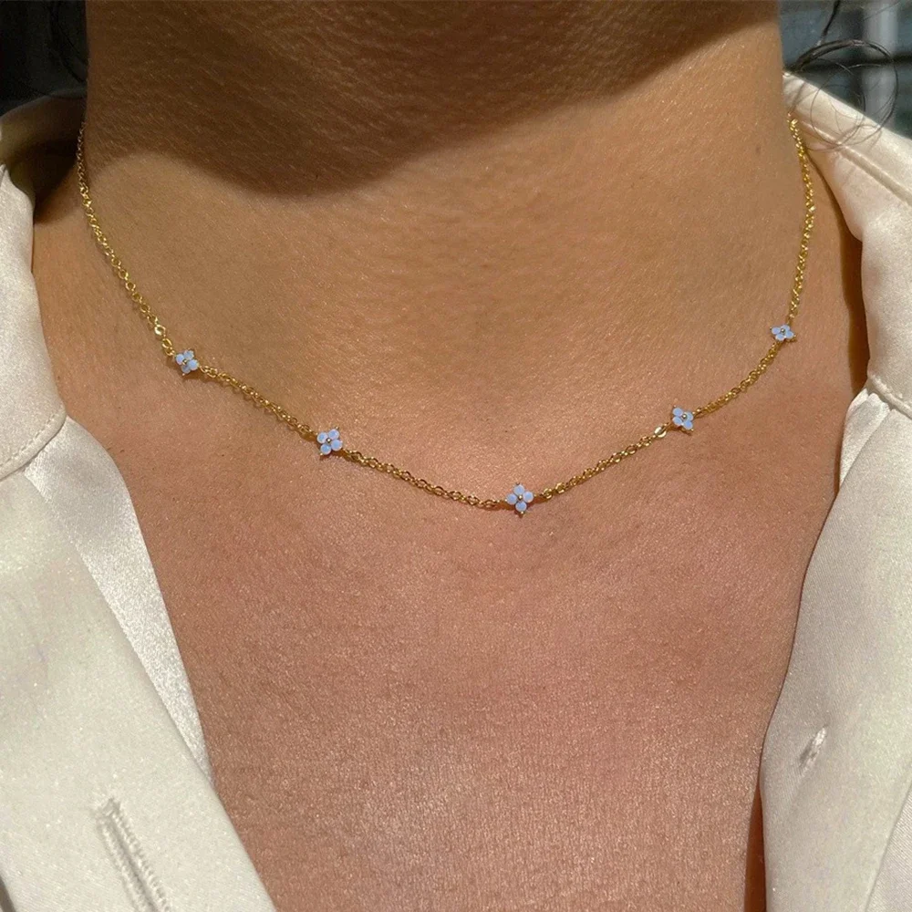 Collier trèfles dorés porté avec une chemise blanche
