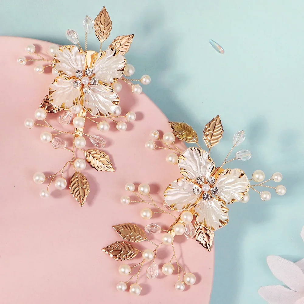 Deux barrettes dorées à fleurs de perles posées sur fond rose